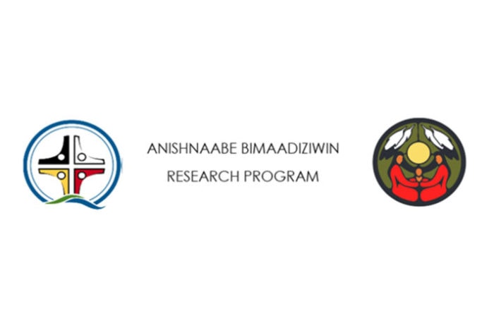 This image contains two logos one for Sioux Lookout Meno Ya Win Health Centre and one for the Sioux Lookout First Nations Health Authority. The logo for Sioux Lookout Meno Ya Win Health Centre consists of concentric blue and greens circles containing the four colours of the medicine wheel - red, white, yellow and black - at the centre. Each colour is represented by a figure consisting of a head and outstretched arms. The figures are aligned so their arms are arranged to make the shape of a cross. The logo for the Sioux Lookout First Nations Health Authority consists of a black circle with a green background. Three figures in red are seated on the ground linking arms, a yellow sun is above them and two white feathers with black tips hang down on either side of the sun.